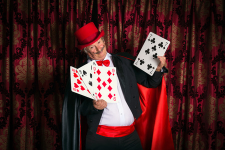 Mature magician on stage performing a magic trick with cardsの写真素材