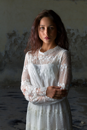 Antique edwardian lace dress worn by a beautiful woman against an old wallの写真素材