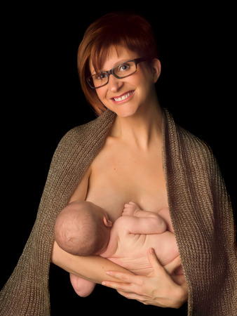 Young mother breastfeeding her 7 week old baby against black backgroundの写真素材