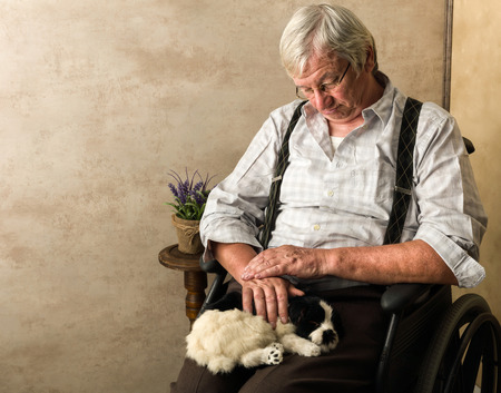 Old pensioner in nursing home sleeping with his dog on his lapの写真素材
