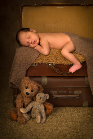 Sleeping African baby of 7 days old lying on a stack of vintage antique suitcasesの写真素材