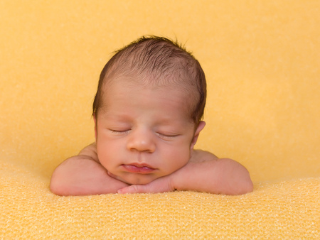 One week old newborn baby of mixed race sleeping on a soft yellow blanketの写真素材