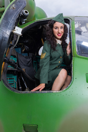 Happy pin-up model in WW2 uniform posing in an old-timer helicopterの写真素材