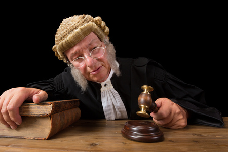 Mature judge with authentic court wig holding a gavel in courtの写真素材