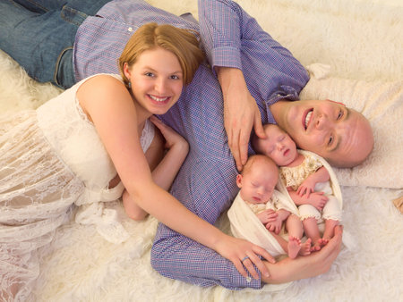 Happy parents posing with their newborn identical twinsの写真素材