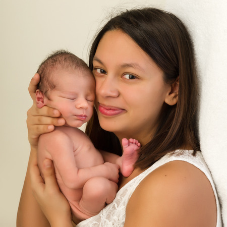 Young mother of mixed race holding her 1 week old newborn baby boy in her armsの写真素材