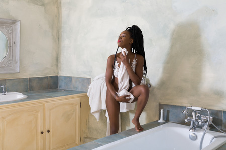 Beautiful young african woman with afro hairstyle in a vintage white bathroomの写真素材