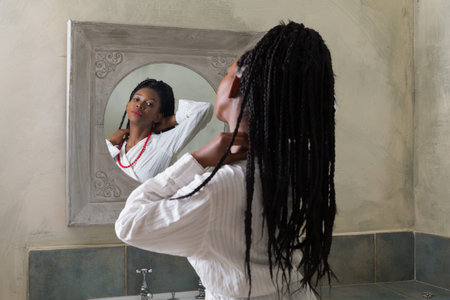 Pretty young african american woman doing her morning routine in front of the bathroom mirror