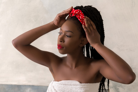 Young woman with afro hairstyle preparing to take a bath in a vintage white bathroomの写真素材
