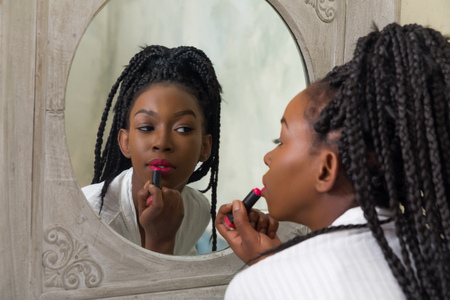Pretty young african american woman doing her morning routine in front of the bathroom mirrorの写真素材