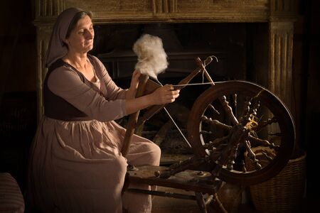 Renaissance Old Master portrait of a woman with antique spinning wheel in front of a fireplaceの写真素材