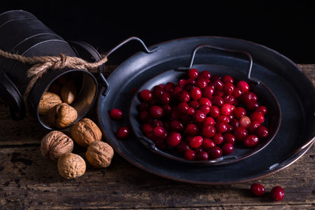 Antique dish and rustic jar filled with fresh cranberries and walnuts for thanksgiving