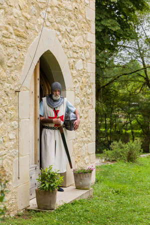 Outdoor pose of a man dressed in authentic Knight Templar outfit or crusader costume standing against a background of a medieval French castleの写真素材