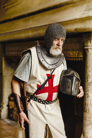 Authentic knight in medieval crusader outfit with helmet, chainmail and sword