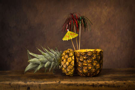 Dark still life with fresh pineapples on an antique wooden tableの写真素材
