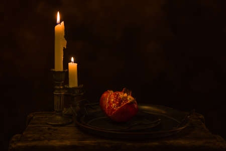 Still life on wooden table with antique plates and a pomegranate cut open.の写真素材