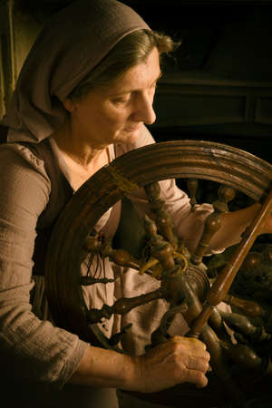 Renaissance Old Master portrait of a woman with antique spinning wheel in front of a fireplaceの写真素材
