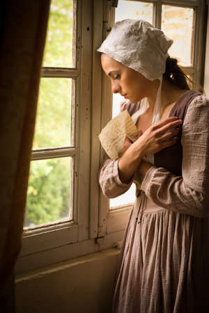 Vermeer style portrait of a young maid in renaissance costume reading a letter at her window