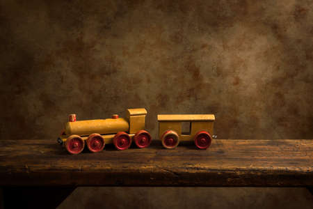 Cute old wooden train toy with red wheels on a rustic old wooden shelf.の写真素材