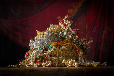 Romantic image of a treasure chest filled with jewellery, precious gems and golden king's crownsの写真素材