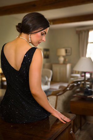 Stunning young woman in black beaded 1920s flapper dress sitting on an old pianoの写真素材