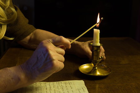 Hand lighting a candle with a matchの写真素材