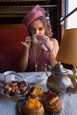 Reenactment scene of a 1920s flapper dress lady enjoying high tea in an authentic 1927 steam train compartmentの写真素材