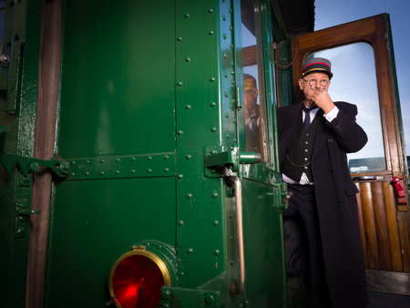 Reenactment scene with authentic 1927 1st class train carriage and a retro train conductor at...