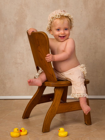 Baby boy of 12 months old sitting on a vintage old wooden chairの写真素材