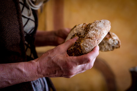 Woman in authentic peasant renaissance costume breaking the bread.の写真素材