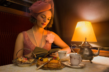 Reenactment scene of a 1920s flapper dress lady enjoying high tea in an authentic 1927 steam train compartmentの写真素材