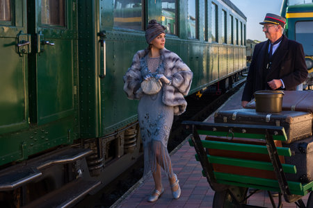 Reenactment scene on the platform near an authentic 1927 first class train wagon where a posh 1920s...