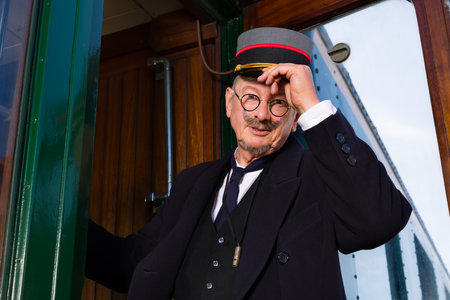Reenactment scene with authentic 1927 1st class train carriage and a retro train conductor at departureの写真素材