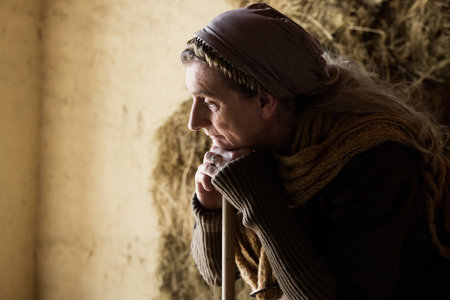Woman in historical medieval costume working with a broom in a hay shedの写真素材