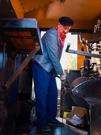 Reenactment scenes of a vintage worker or machinist in an authentic 1922 locomotive with restored engineの写真素材