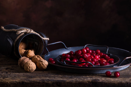 Still life with 2 rustic plates filled with fresh cranberries on an antique wooden tableの写真素材