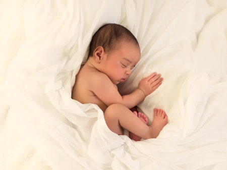 Cute little sleeping African biracial newborn baby sleeping on a white soft blanketの写真素材