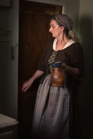 Lady in medieval costume holding a stone jugの写真素材