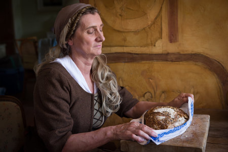 Woman in authentic peasant renaissance costume holding bread.