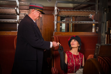 Reenactment scene of a vintage steam train conductor in a 1927 authentic first class train interior