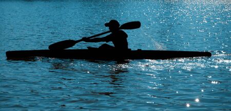 A black silhouette of a sportsman on a paddle (kayak)の写真素材