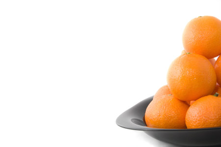 Tasty orange tangerines on black plate isolated on whiteの写真素材