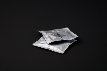 Two condoms isolated on black backgroundの写真素材