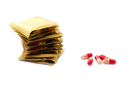 Condoms in a stack and oral contraceptive pills isolated on whiteの写真素材
