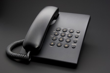 Black office phone with cord isolated on black backgroundの写真素材