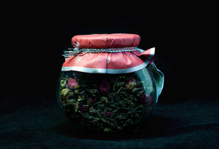 Misterious chinese taste - jar of green tea with rose, lightened with green light in the darkの写真素材