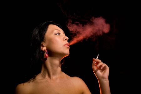 Thoughts of passion - smoking young female in red lightの写真素材