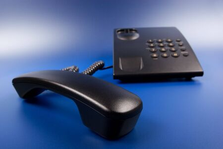 Shiny and successful business - black office phone and handset on blue background beautifully lightedの写真素材
