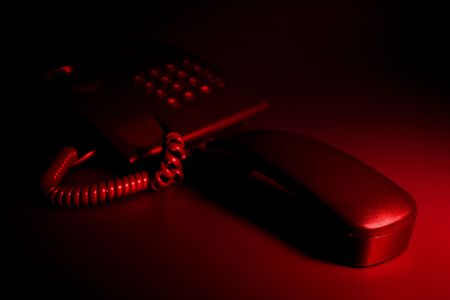 Urgent anxious night phone call - black telephone under red light の写真素材
