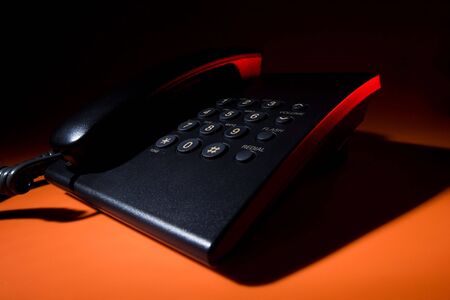 Office hell - corded phone on orange background lighted with redの写真素材